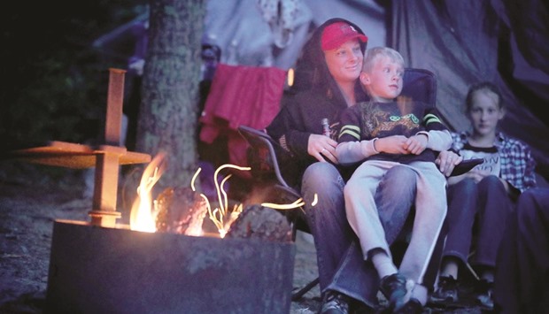 BONFIRE:  Caron Daniel of Duluth snuggles by the campfire with her son Ayden, 8, at the Windmill Rock campground on Rainy Lake.