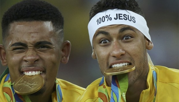 Neymar and Gabriel Jesus of Brazil bite their medals