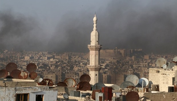 Smoke from burning tyres rises near a minaret of a mosque, which activists said are used to create smoke cover from warplanes, in Aleppo.