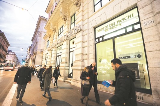 Pedestrians pass a Monte dei Paschi di Siena bank branch in Rome. The bank, which has been bailed out twice by the government since 2009, says it plans to sell as much as u20ac5bn ($5.6bn) of stock if it can offload a bad-loan portfolio.
