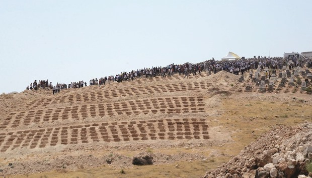 People wait close to empty graves at a cemetery during the funeral for the suicide bombing victims.