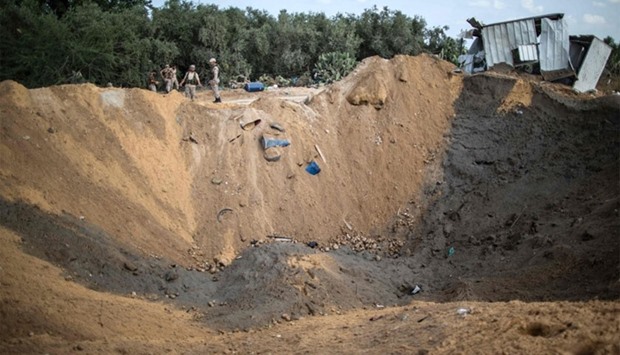 Palestinian militants of the Islamic Jihad movement arrive to inspect a crater on August 22, 2016 in Beit Lahia in the northern Gaza Strip, following an Israeli airstrike the day before that targeted Hamas positions in the Gaza Strip in response to a rocket fired from the Palestinian enclave hits the Israeli city of Sderot.  AFP