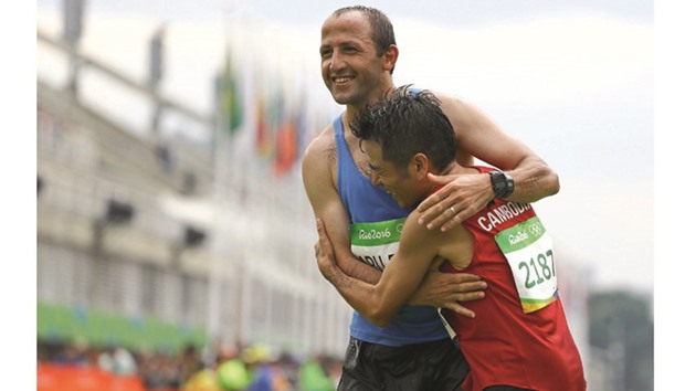 Second to last Kuniaki Takizaki of Cambodia (right) embraces last finisher Methkal Abu Drais of Jordan. (Reuters)