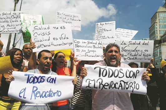 Opposition supporters shout slogans during a protest due to the lack of medicines and to demand a referendum to remove President Nicolas Maduro in Caracas. The placards read, u201cEveryone with the recallu201d.