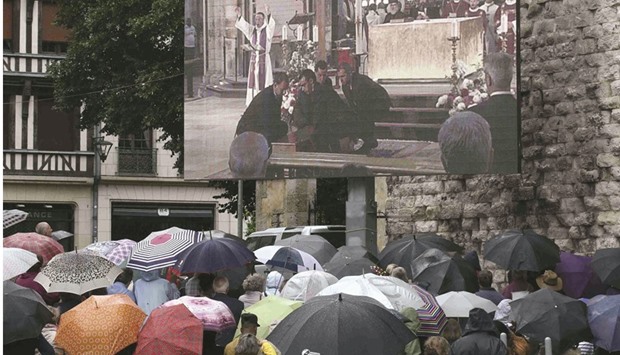 mosques,u201d the minister said.  Mourners gather in the rain near a giant screen outside the cathedral in Rouen, during a funeral service in memory of slain French parish priest Father Jacques Hamel.