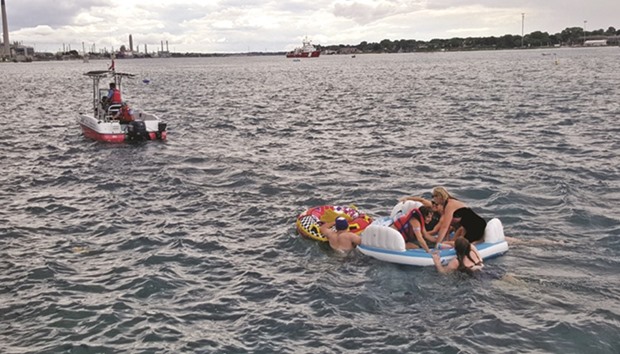 A Canadian Coast Guard ship tows floatation devices used by US partiers to the Canadian side of the St. Clair River between Michigan and Ontario on Sunday. About 1,500 Americans ended up in Canada after getting hit by strong wind and rain.