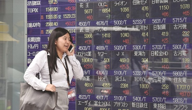 A woman passes before a share prices board in Tokyo. The Nikkei 225 closed up 0.3% to 16,598.19 points yesterday.
