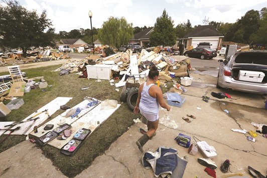 A woman walks through her flood-damaged frontyard at the South Point subdivision in Denham Springs, Louisiana.