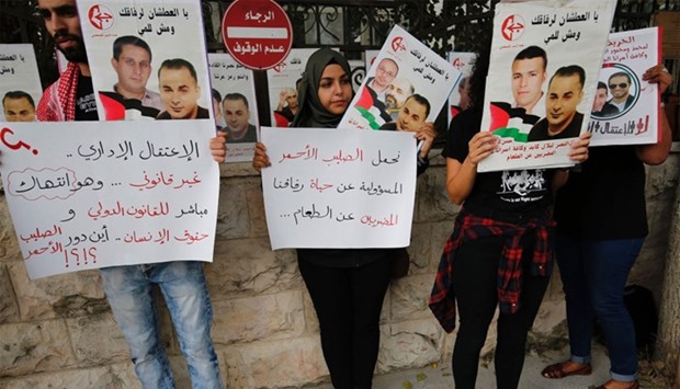 Palestinians hold posters of Palestinian prisoner Bilal Kayed, who has been on hunger strike for 71 days, as they demonstrate in front of the Red Cross headquarters in the West Bank city of Ramallah in support of prisoners on hunger strike in Israeli jails.