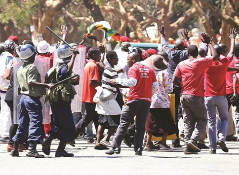 Anti-riot police use batons to disperse demonstrators in Harare.