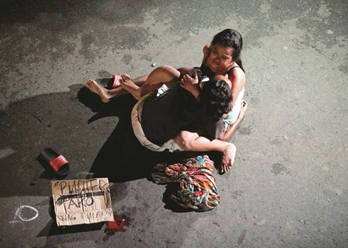 Jennelyn Olaires, 26, cradles the body of her partner, who was killed on a street by a vigilante group, according to police, in a spate of drug related killings in Pasay city, Metro Manila, Philippines on July 23, 2016. A sign on a cardboard found near the body reads, u201cPusher Akou201d, which translates to u201cI am a drug pusher.u201d