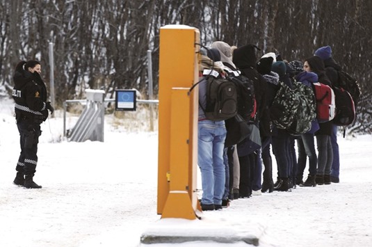 Migrants receive instructions from a Norwegian police officer at the Storskog border.