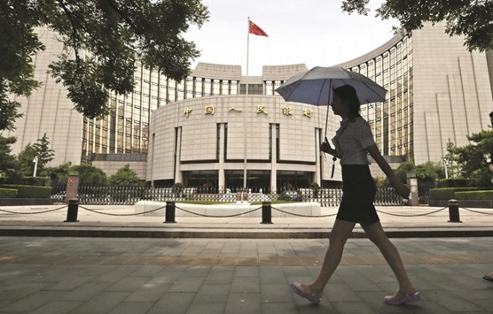 A pedestrian walks past the Peopleu2019s Bank of China in Beijing. The PBoC met major banks on Wednesday to discuss management of liquidity in Chinese money markets amid rising speculation over whether Beijing would continue its monetary policy easing or not, the sources said yesterday.