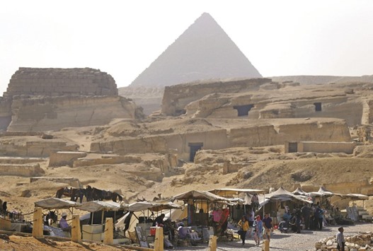 Souvenir vendors wait for tourists in front of the Giza pyramids on the outskirts of Cairo on March 2, 2016. Tourism, a mainstay of the economy, has been hit hard since the 2011 revolution that overthrew Hosni Mubarak, with many of Egyptu2019s renowned historical sites, from the pyramids at Giza to the Valley of the Kings in Luxor, suffering a decline in foreign visitors.