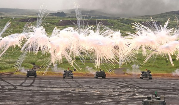 Japanese Ground Self-Defence Force tanks move amongst an umbrella of barrage during an annual live fire exercise at the Higashi-fuji firing range in Gotemba, at the foot of Mount Fuji in Shizuoka prefecture.