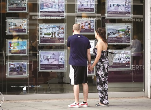 A couple scan an estate agents window in London.