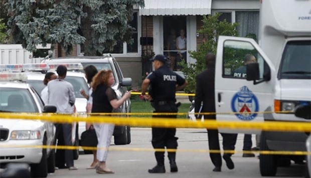 People watch from their front door as police stand at a crime scene where three people died in an incident involving a crossbow, in the Scarborough suburb of Toronto.