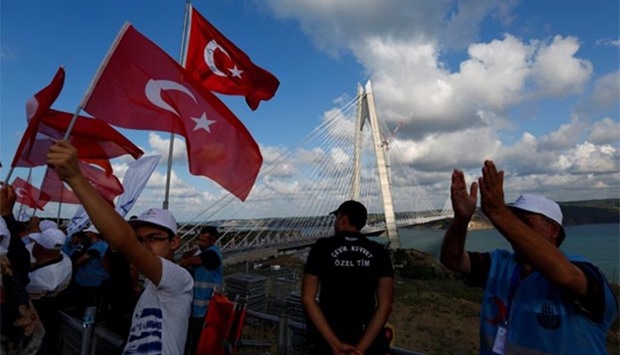 People wave Turkish flags during the opening ceremony of Yavuz Sultan Selim bridge, the third bridge over the Bosphorus linking Istanbul's European and Asian sides, on Friday.