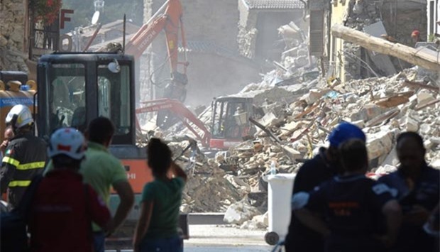 Firefighters and emergency rescuers search for victims under the remains of a building in the damaged central Italian village of Amatrice on Friday.