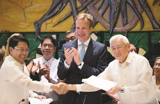 Philipines Presidential Peace Adviser Jesus Dureza (left) and the Chairman of the National Democratic Front of Philippines (NDFP) Luis Jalandori (right), shake hands in front of the Norwegian Minister of Foreign Affairs Boerge Brende after signing a joint declaration in which both parties undertake unilateral ceasefires without time constraints yesterday in Oslo.
