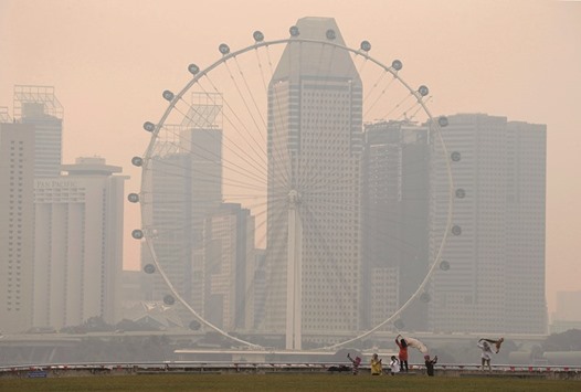 People take photos near the Singapore Flyer observatory wheel shrouded by haze.