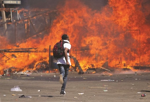 An opposition supporter runs near a burning barricade during clashes with police.