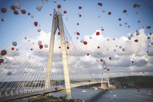 Red and white air-balloons flying in the sky next to the Yavuz Sultan Selim bridge in Istanbul during its inauguration. The bridge u2013 technically a hybrid between a suspension and cable-stayed bridge u2013 is an architectural marvel spanning the steep banks of the Bosphorus at the entrance to the Black Sea.
