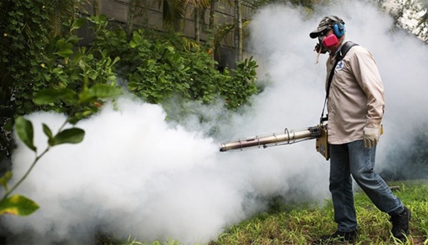 Uses a blower to spray pesticide to kill mosquitos in the Miami Beach neighborhood