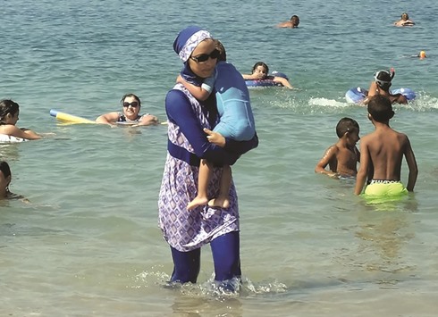A woman in a burqini walks yesterday in the water on a beach in Marseille, France, a day after the countryu2019s highest administrative court suspended a ban on full-body burqini swimsuits.