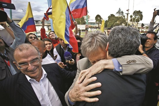 The head of the Colombian government delegation for peace talks with the Farc guerrillas Humberto de la Calle (left) and Colombian High Commissioner for the Peace Sergio Jaramillo (right) receive a hug by Colombian former presidential candidate Antanas Mockus upon their arrival from Cuba in Bogota on Friday.