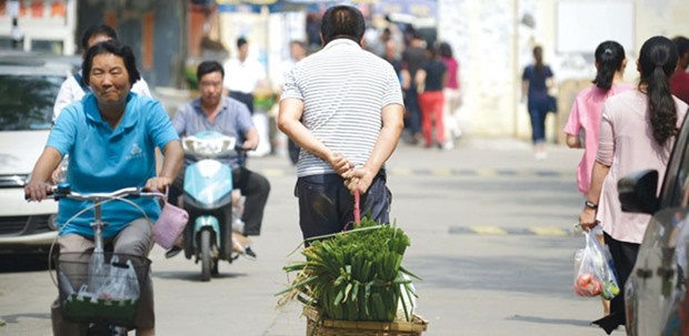 This picture taken on September 8, 2015 shows a man pulling a basket of leeks as he walks along a road near an open market in Beijing. Over the past decade, Chinau2019s total debt grew 465%. Debt rose to 247% of gross domestic product in 2015, from 160% in 2005. Despite that rapid growth, household debt in China is far below levels in the US before the subprime crisis. At its 2007 peak in the US, household debt reached almost 100% of GDP. Whatu2019s more, in China household savings are twice as large as its debt.