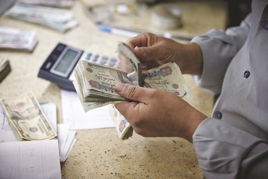 A man counts Egyptian pounds banknotes at a foreign currency exchange bureau in Cairo. With its currency trading near a record low in the black market, reserves to cover just three months of imports and a widening current-account deficit, pressure is mounting on the most populous Arab state to devalue the pound to alleviate a dollar shortage that prompted officials to seek help from the International Monetary Fund.