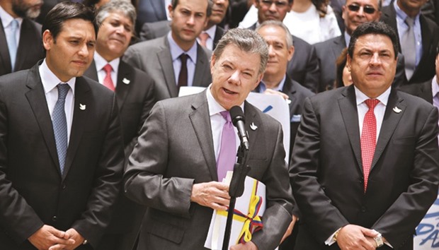 Colombian President Juan Manuel Santos (centre) holds a copy with the final text of the peace agreement with the Farc guerrillas, before giving it to the president of the National Congress, senator Mauricio Lizcano (left), in Bogota last Thursday.