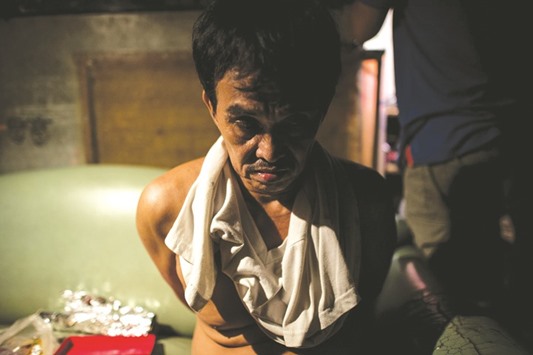 This photo taken on August 27, 2016 shows an alleged drug pusher sitting on a sofa after he was detained for possession of illegal drugs during a police operation in Manila.