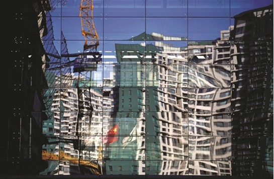 A construction site and a residential building are reflected on the glass wall of a building in Beijing.