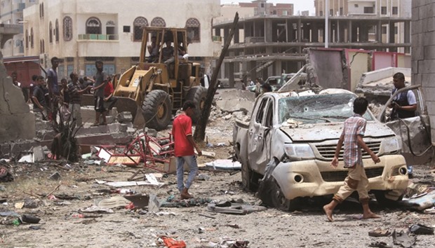 Yemenis inspect the site of a suicide car bombing claimed by the Islamic State group yesterday at an army recruitment centre in the southern Yemeni city of Aden.