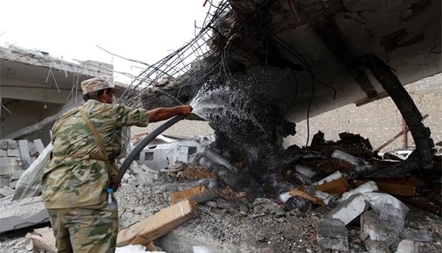 A Yemeni man in military fatigue puts out a flame in a building in Sanaa on Monday after it was reportedly hit by a Saudi-led coalition air strike.