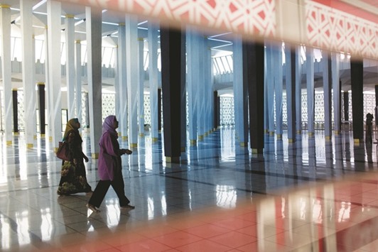Women are reflected in a window as they walk inside the National Mosque of Malaysia in Kuala Lumpur. While demand for Shariah-compliant investments is rising, about $9.5tn of Islamic wealth still remains outside the Shariah finance industry, Malaysia International Islamic Financial Centre estimated in February.