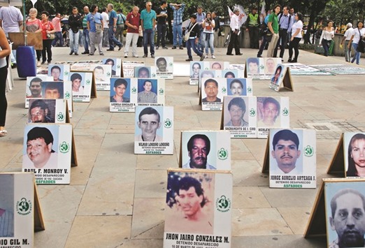 People stand near photographs of missing persons to mark the International Day of the Victims of Enforced Disappearances in Medellin, Colombia.
