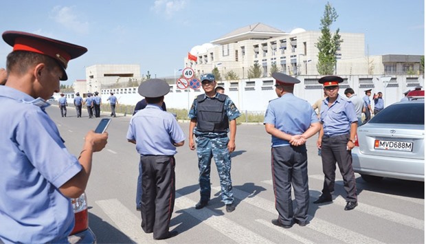 Police officers gather outside the Chinese embassy in Bishkek yesterday after a van driven by a suicide bomber exploded after ramming through a gate at the embassy.
