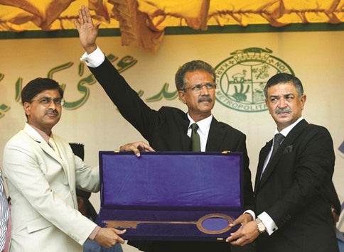 Waseem Akhtar (centre), mayor of Karachi and member of the Muttahida Qaumi Movement (MQM), waves as he receives a symbolic Karachi Key from Laeeq Ahmed (left), outgoing administrator Karachi Metropolitan Corporation (KMC), after the oath taking ceremony in Karachi, yesterday.