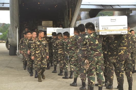 Soldiers carry caskets containing bodies of colleagues, killed in an encounter with Muslim extremist Abu Sayyaf group, into a C-130 cargo plane at Jolo airport in Sulu province on the island of Mindanao yesterday.