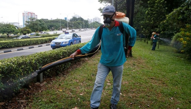 A worker sprays insecticide along the perimeter of a construction site, at an area where locally transmitted Zika cases were discovered in Singapore August 30, 2016