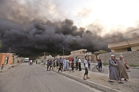 Residents gather in the street in the city of Qayyara, Iraq. Picture taken on Monday. Oil wells were set ablaze by Islamic State militants before fleeing the oil-producing region of Qayyara.
