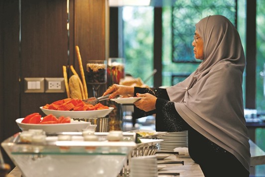 A Muslim visitor takes food from a platter for her breakfast at the Al Meroz hotel in Bangkok.