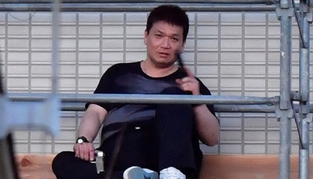 Yasuhide Mizobata, a murder suspect of a fatal shooting in the city of Wakayama, holds guns as he sits on scaffoldings of an apartment building in a standoff after he fired at a police car and escaped, in Wakayama, western Japan.  Reuters