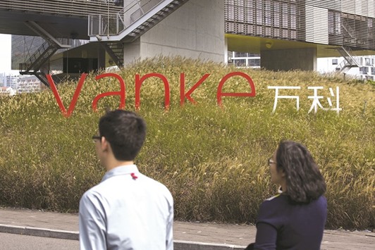 Employees walk past a logo of Vanke at its headquarters in Shenzhen, Guangdong province. Vanke, which has a market value of nearly $40bn and annual revenue of $28bn, is battling financial conglomerate Baoneng which has acquired 25% of the company over the past year and has tried to oust its board.