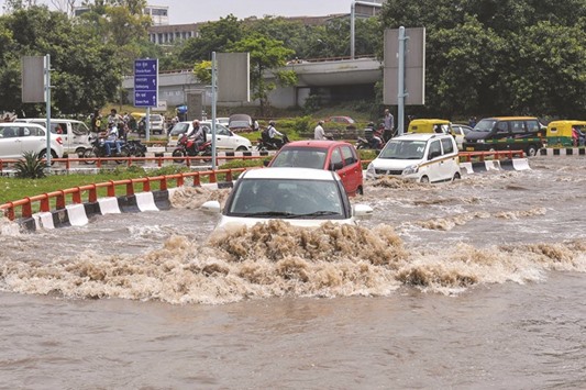 Motorists make their way through floodwaters at a major intersection in New Delhi yesterday.