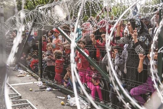 A September 16, 2015, file photo of refugees standing behind a fence at the Hungarian border with Serbia near the town of Horgos.