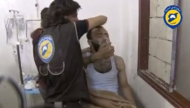 A still image taken on August 2, 2016 from a video said to be taken on August 1, 2016 posted on social media shows two men standing over a man on a bed, making him sit up as he breathes through a mask in what is said to be in Saraqeb, Idlib province, Syria.